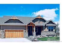 Charming home with wood trim, stone accents, beautiful landscaping, and a wooden garage door at 1405 Swan Peter Dr, Berthoud, CO 80513