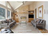 Bright living room featuring a stone fireplace, vaulted ceilings, and large windows with mountain views at 230 Cactus Ct, Boulder, CO 80304