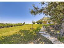 Landscaped yard with stone steps leading to a charming yellow home under a clear blue sky at 34 S Raleigh St, Denver, CO 80219