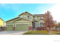 Two-story house with green siding, brick accents, and a three-car garage at 6918 Purdue Ave, Firestone, CO 80504