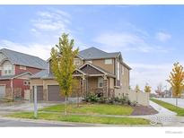 Charming two-story home with a two-car garage, stone accents, and a cozy front porch, complemented by well-maintained landscaping at 1127 Highlands Dr, Erie, CO 80516