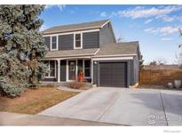 Two-story house with a gray exterior, attached garage, and landscaping at 908 Clover Cir, Lafayette, CO 80026