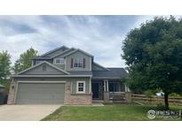 Two-story house with gray siding, brick accents, and a landscaped lawn at 136 Wiggett Ct, Erie, CO 80516