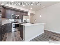 Modern kitchen with island, stainless steel appliances, and dark cabinetry at 410 High Point Dr # 103, Longmont, CO 80504