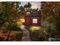 Charming red two-story home with metal roof and a beautifully landscaped front yard at 704 E Baseline Rd, Lafayette, CO 80026