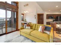 Bright living room with comfy yellow sofa and access to a balcony at 1891 Ski Hill Rd # 7408, Breckenridge, CO 80424