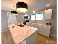 Modern kitchen with white cabinets, quartz countertops, and stainless steel appliances at 1022 Kansas Ave, Longmont, CO 80501