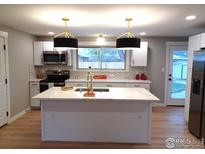 Modern kitchen with white cabinets, stainless steel appliances, and a large island at 1022 Kansas Ave, Longmont, CO 80501