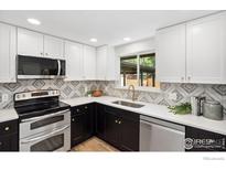 Stylish kitchen showcasing stainless appliances, tile backsplash, and white and black cabinets, plus a window at 1232 Lincoln St, Longmont, CO 80501