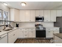 Bright kitchen features white cabinets, stainless steel appliances, and modern subway tile backsplash at 1040 Coronado S Pkwy # D, Denver, CO 80229