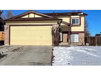 Two-story house with attached garage, snow-covered lawn, and brick accents at 12117 Newport Dr, Brighton, CO 80602