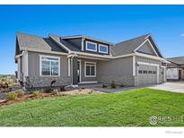 Charming home featuring manicured lawn, gray siding, stone accents, and a two-car garage at 1369 Burt Ave, Berthoud, CO 80513