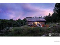 Beautifully lit exterior with manicured landscaping and wooded backdrop at dusk at 3500 Bison Dr, Boulder, CO 80302