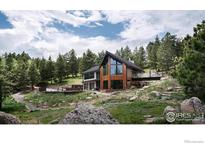 Stunning mountain home with expansive windows and a unique bridge walkway surrounded by lush forest at 3500 Bison Dr, Boulder, CO 80302