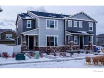 Two-story townhome with gray siding, stone accents, and a snowy front yard at 5108 Buckwheat Rd, Brighton, CO 80640