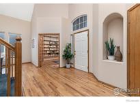 Bright entryway with hardwood floors, built-in shelving, and access to a home office at 628 Saint Andrews Dr, Longmont, CO 80504