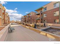 Exterior pathway with landscaping, bench, and building views at 1053 W Century Dr # 102, Louisville, CO 80027