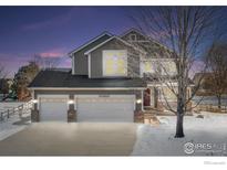 Two-story house with a gray exterior, two-car garage, and snowy front yard at 4964 Shenandoah Ave, Firestone, CO 80504
