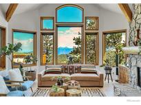 Bright living room featuring a large picture window with mountain views and a telescope, a comfortable sofa, and a stone fireplace at 57 Whispering Pines Rd, Boulder, CO 80302