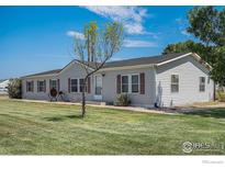 Charming single-story home with gray siding, lawn and shuttered windows nestled under a sunny blue sky at 8260 County Road 39, Fort Lupton, CO 80621