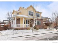 Two-story house with a brick and yellow facade, front porch, and snowy landscaping at 11830 Raleigh Pl, Westminster, CO 80031