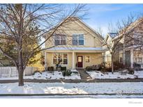 Charming two-story yellow home with snowy front yard and white picket fence at 1494 Yaupon Ave, Boulder, CO 80304