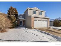 Brick two-story house with attached garage, landscaping, and snow-covered yard at 1836 Juniper St, Longmont, CO 80501