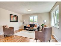 Bright living room with hardwood floors, comfy seating, and large windows at 2471 Harlan St, Edgewater, CO 80214