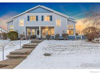 Charming two-story home with snow-covered yard, walkway, and lovely architectural details at 1419 Red Mountain Dr # 13, Longmont, CO 80504