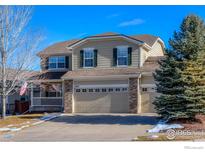 Two-story house with a beige exterior, a three-car garage, and a manicured lawn at 1420 Hickory Dr, Erie, CO 80516