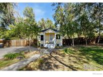 Cute yellow house with a well-maintained lawn and mature trees at 305 Jackson Ave, Firestone, CO 80520