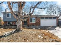 Ranch style home with brick and gray siding, mature tree, and a two-car garage at 399 Jackson Cir, Louisville, CO 80027