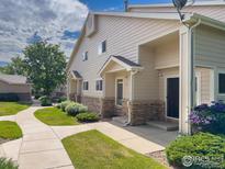 Tan two-story townhome with brick accents and a paved walkway at 1601 Great Western Dr # R1, Longmont, CO 80501