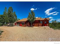 Charming log home featuring bright red doors and a spacious gravel yard, perfect for a country lifestyle at 2244 County Road 12, Erie, CO 80516