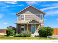 Two-story house with light brown siding, teal door, and landscaping at 3088 Rose Hill St, Strasburg, CO 80136