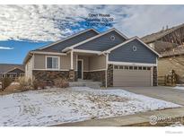 Tan two-story house with gray accents and stonework, two-car garage, and partially snow-covered front yard at 413 Canyonlands St, Berthoud, CO 80513