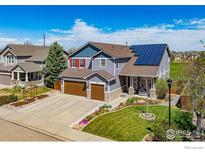 Two-story house with solar panels, landscaped yard, and attached garage at 909 Glenarbor Cir, Longmont, CO 80504