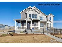 Two-story craftsman style home under construction with gray and white siding, front porch, and black fence at 916 Andrews Crest Dr, Berthoud, CO 80513