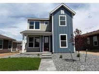 Charming two-story home featuring a combination of gray and blue siding, a well-manicured lawn, and a welcoming entrance at 2303 Peregrine Dr, Brighton, CO 80601