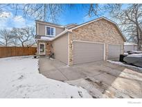 Brick front exterior with two-car garage and snow-covered yard at 421 Stevens Cir, Platteville, CO 80651