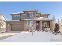 Two-story house with brick and siding, attached garage, and snow-covered front yard at 8780 Foxfire St, Firestone, CO 80504