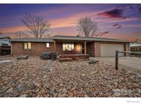 Brick ranch home with landscaped front yard, featuring a large planter and spacious driveway at 1221 Cedar Dr, Berthoud, CO 80513