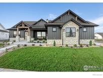 Stunning farmhouse exterior with stone accents and a spacious lawn at 1422 Eliza Ave, Berthoud, CO 80513