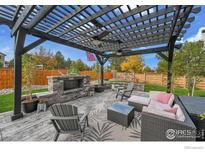 Covered patio with fireplace, seating area, and pergola at 16060 E Fairway Dr, Commerce City, CO 80022