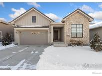 Two-story house with stone and wood exterior, two-car garage, and snowy front yard at 3351 Heron Lakes Pkwy, Berthoud, CO 80513