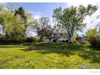 A lush backyard with mature trees, a fire pit, and a sunroom addition to the home at 4667 Ashfield Dr, Boulder, CO 80301