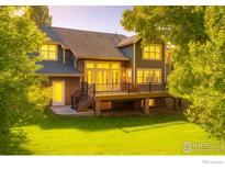 Inviting backyard with a spacious deck, lush lawn, and mature trees creates a private outdoor oasis at 6345 Swallow Ln, Boulder, CO 80303