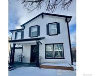 Two-story house with white siding, black accents, and a snow-covered front yard at 10676 Durango Pl, Longmont, CO 80504