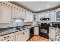 Well-lit kitchen with white cabinets, granite countertops, and stainless steel appliances at 246 S 22Nd Ave, Brighton, CO 80601