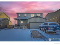 Two-story house with gray siding, snowy front yard, and attached garage at 6004 Sandstone Cir, Erie, CO 80516